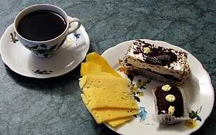 closeup photo of sliced cake on plate near teacup with saucer