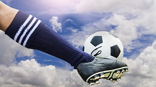 person kicking soccer ball during daytime HD wallpaper