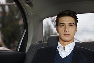 man wearing black blazer and white collared shirt sitting inside the car