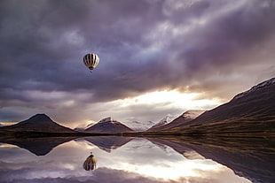 hot air balloon flying above the body of water