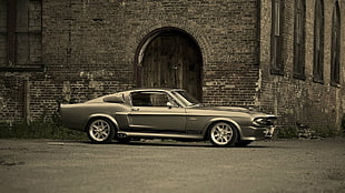 gray Ford Mustang Grande Fastback coupe parked near concrete building during daytime