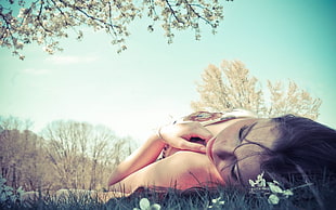 woman lying on green grass field under tree during daytime