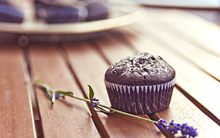 chocolate muffin beside Lavender flower on brown wooden surface
