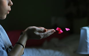 kid blowing pink paper heart cuts
