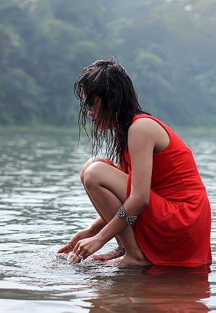 woman wearing red dress sitting on a water