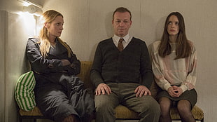 man in between two woman while sitting on sofa