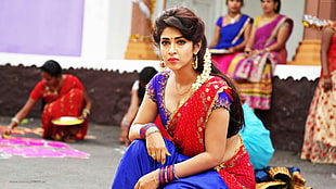 woman wearing red and blue ghagra choli traditional Indian dress crouching on floor