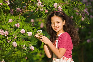 girl in white and pink top holding white petaled flower photopgraphy