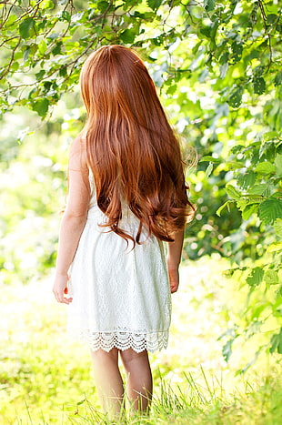 girl in white dress surrounded by green leaf