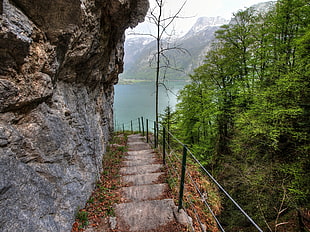 grey concrete stair beside grey rocky mountain near water digital wallpaper