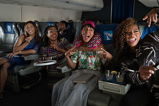 four women smiling while sitting inside plane