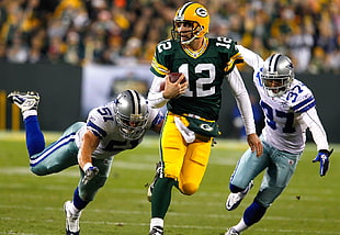 Green Bay Packers player holding football running on grass field chased by two Dallas Cowboys players during daytime photo