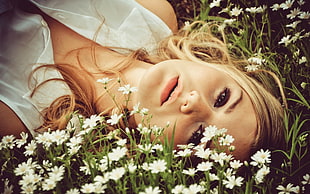 woman laying down on white roses field