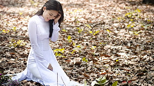 woman wearing white long-sleeved dress kneeling on the ground