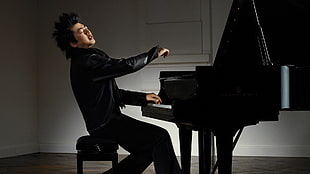 man wearing black leather jacket playing piano