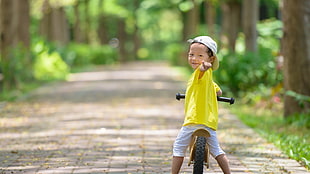 boy in yellow shirt riding a bike during daytime
