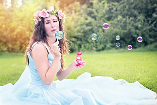 woman in blue sleeveless dress holding bubble maker
