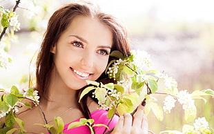 photo of smiling woman in front of plant under the sunlight