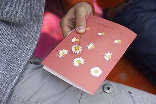 person holding red and white floral card