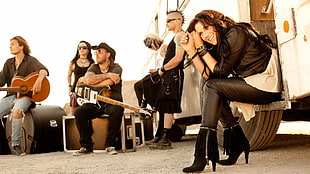 black haired woman wearing black leather jacket on sitting on white trailer