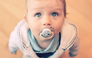 close up photography of baby using teether