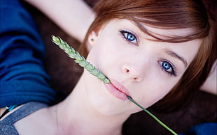 woman with blue eyes biting the plant