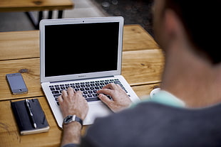 man typing on silver laptop computer