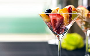 selective focus of clear martini glass with fruits near window