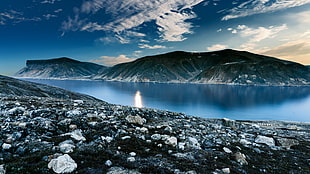 landscape photo of black mountain surrounded by body of water during daytime HD wallpaper
