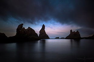silhouette of rock monument beside water, night, nature, clouds, sky