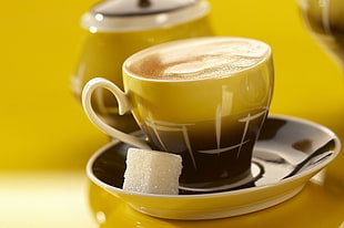 black and yellow ceramic mug with cappuccino coffee on saucer