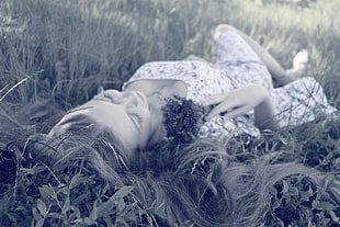 woman in floral scoop-neck dress lying on grass field close-up photo during daytime