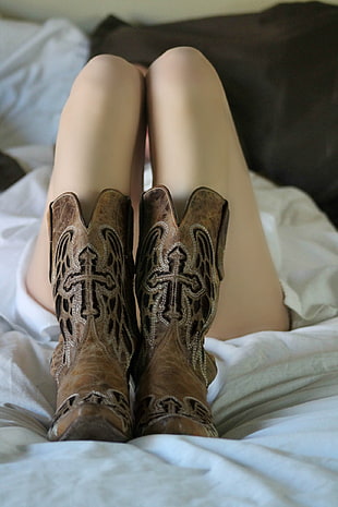 woman lying in bed with brown leather cowboy boots