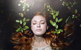 woman in water with her face surrounded with leaves