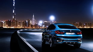 blue BMW sedan on roadway at nighttime