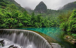 time-lapse photography of waterfalls surrounded by green trees and mountains