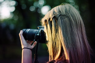 macro photography of woman hold black DSLR camera