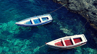 two red and blue dinghy boats near gray rock, boat