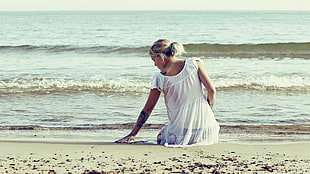 photo of woman sitting on sand during daytime