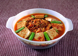 photo of kimchi and tofu soup dish in white ceramic bowl