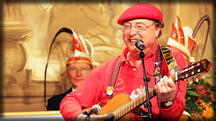 man wearing red dress shirt and beret holding guitar