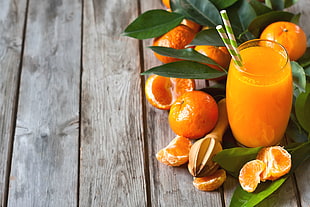 orange juice in glass surrounded by orange fruit