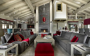 rectangular brown wooden table between two gray fabric sofas in front of fireplace
