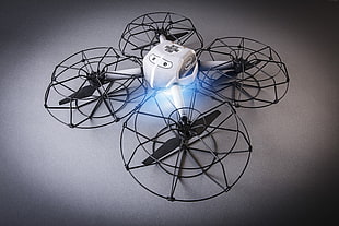 turned on white and black quadcopter drone on gray platform
