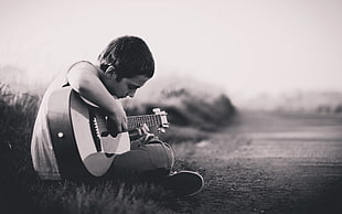 grayscale photo of boy playing guitar