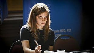 brown haired woman in black shirt holding black pen