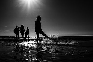 grayscale photo of people standing on body of water