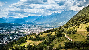 aerial photo of mountain with green trees near city