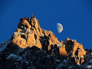 photo of brown concrete mountain with half moon during daytime