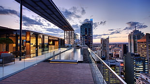 balcony swimming pool overlooking high-rise buildings under blue and white clouds during daytime HD wallpaper